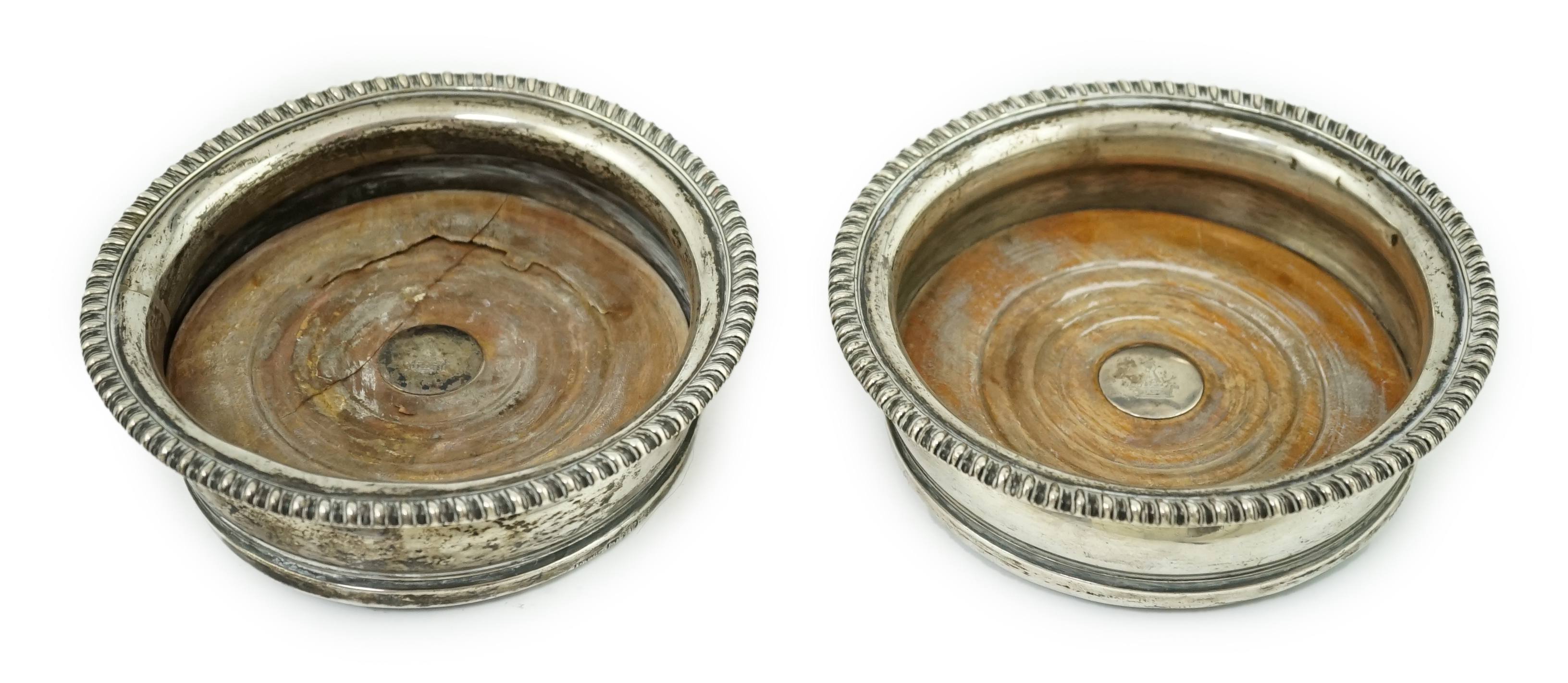 A pair of George III silver wine coasters, by John Roberts & Co, with gadrooned borders and turned wooden bases, Sheffield, 1810, diameter 15.9cm. Condition - poor